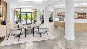 Eine großzügige Lobby mit einer Sitzecke, großen Fenstern und einer Rezeption.