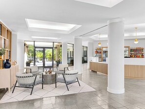 Eine großzügige Lobby mit einer Sitzecke, großen Fenstern und einer Rezeption.
