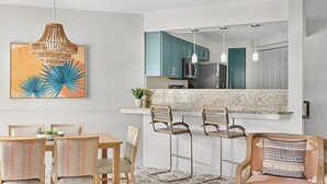 Eine moderne Küche mit türkisfarbenen Schränken, einem Edelstahlkühlschrank und einer Bar mit Hockern.