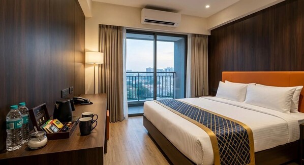 Habitación de hotel con una cama, un escritorio con cafetera, una lámpara y vistas a la ciudad a través de un ventanal grande.