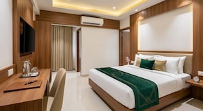 A hotel room with a bed, bedside table, TV, and a desk with a chair.