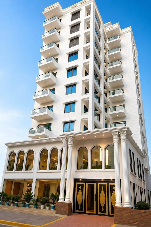 A multi-story hotel with a white facade, large windows, and a classical entrance with columns.