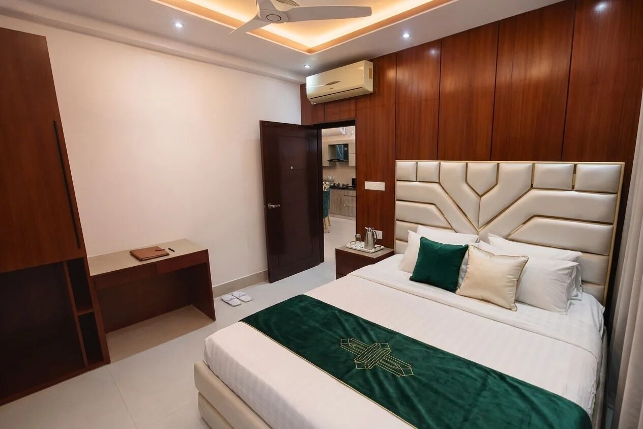 A hotel room with a bed, bedside table, and a desk.