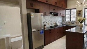 A modern kitchen with dark wooden cabinets, a stainless steel refrigerator, and a central island with a vase. - Royal Richmond Hotel (Dhaka)