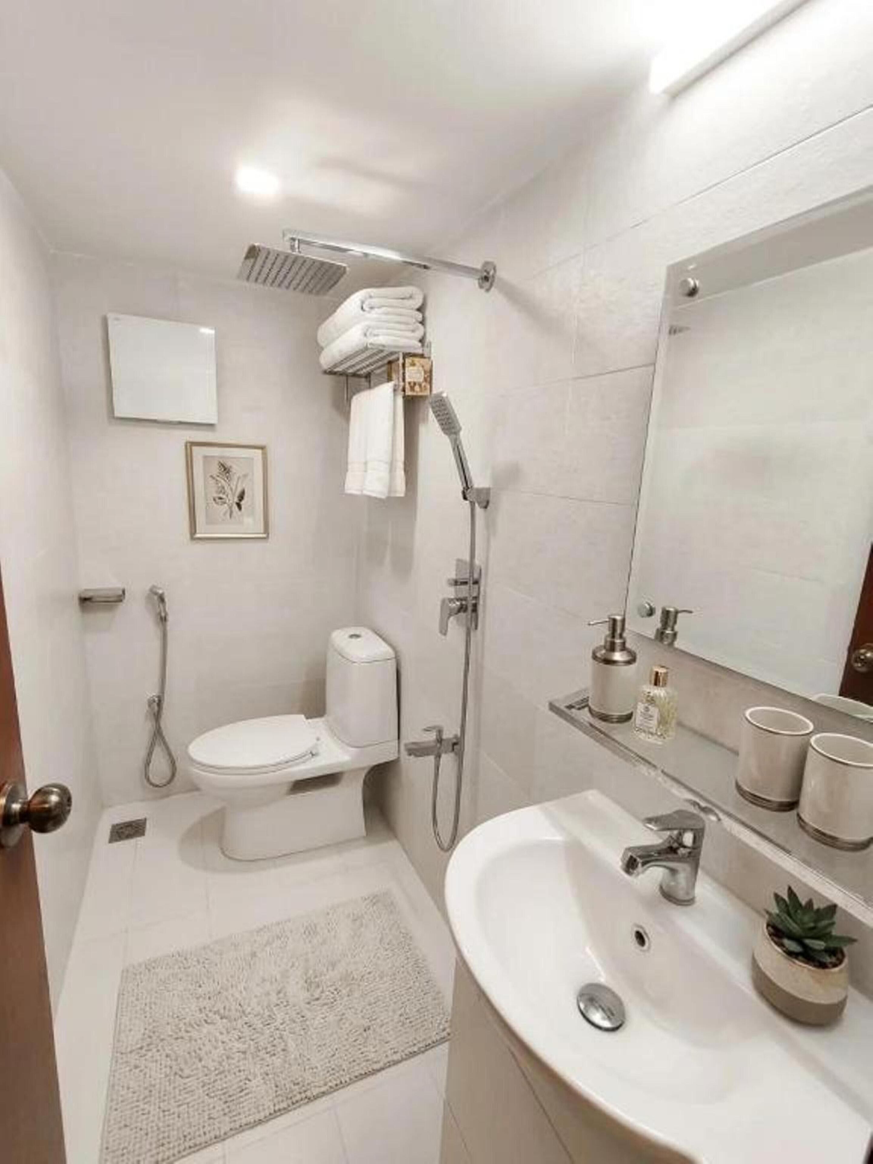 A modern bathroom with a toilet, bidet, shower, and sink.