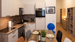 Eine moderne Küche mit Essbereich, Holzschränken, einer Mikrowelle und einer Kaffeemaschine.