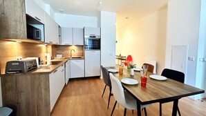 Eine moderne Küche mit weißen Schränken, einer Holzarbeitsplatte und einem Essbereich mit einem Holztisch und Stühlen.