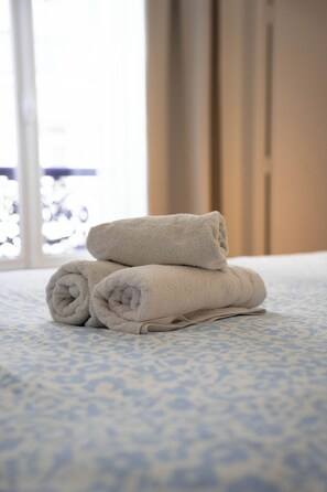A bed with a patterned bedspread and two rolled towels stacked on top of each other. - Townhouses for 8 people in the Foch neighborhood, 16th arrondissement (Paris)