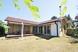 A two-story house with a tiled roof, a covered patio, and a fenced yard. - Modernly Furnished Double Bungalow With Terrace in the Mirow Holiday Park (Mirow)
