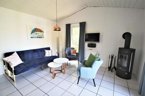 A living room with a sofa, two chairs, a TV, and a fireplace. - Modernly Furnished Double Bungalow With Terrace in the Mirow Holiday Park (Mirow)