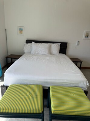 A bed with white bedding, two striped cushions, and a wooden headboard. - Cozy 2-bedroom house in amazing Jolly Harbour with AC (Jolly Harbour)
