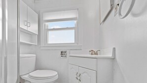 Ein helles Badezimmer mit Toilette, Fenster und Waschbecken.