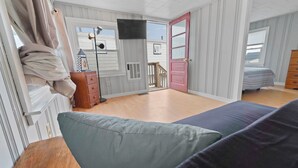 Ein Zimmer mit einem Bett, einem Schminktisch, einem Fernseher und einem Fenster mit Blick nach draußen.