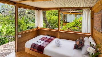 A bedroom with a wooden bed, a view of greenery, and a woven rug.