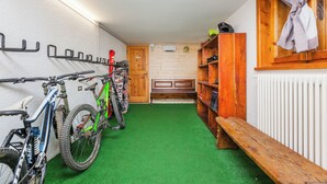 Una stanza con pavimento in erba sintetica verde, panche di legno, una panca con un asciugamano e un portabiciclette a muro con biciclette.