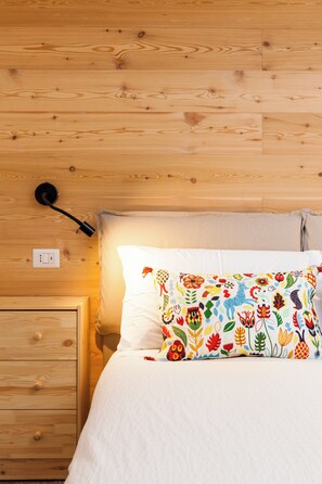 Eine Holzwand mit einem Bett, einem Nachttisch und einer Lampe.