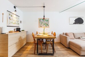 A dining area with a wooden table, chairs, and a hanging light fixture. - Spacious apartment with 2 bathrooms and a view of the mountains. Large lawn on the property (Teola)