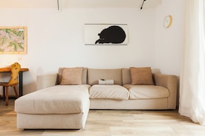 Ein Wohnzimmer mit einer Couch, einer Karte an der Wand und einer Uhr.