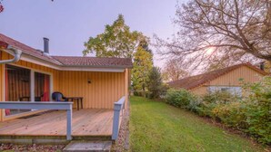 Une maison en bois avec un porche, une petite table et une chaise.
