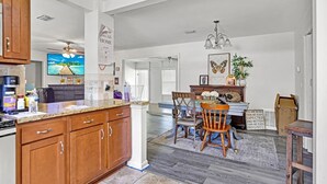 A spacious kitchen with wooden cabinets, a dining area with a table and chairs, and a living room with a ceiling fan and chandelier. - Jax and Relax: 3-bedroom house in Jacksonville (Jacksonville)