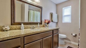 A bathroom with a granite countertop, a large mirror, a toilet, and a window with blinds. - Jax and Relax: 3-bedroom house in Jacksonville (Jacksonville)