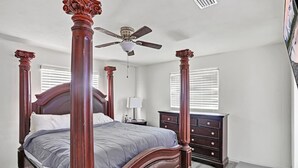 A bedroom with a four-poster bed, a ceiling fan, a nightstand, and a dresser. - Jax and Relax: 3-bedroom house in Jacksonville (Jacksonville)