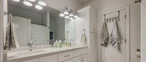 A bathroom with a large mirror, white cabinets, a sink, and a towel rack.