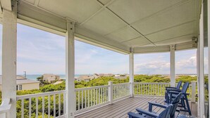 A covered porch with a view of the sea and houses. - La Vie En Bleu - Oceanview Luxury Escape (Surf City)