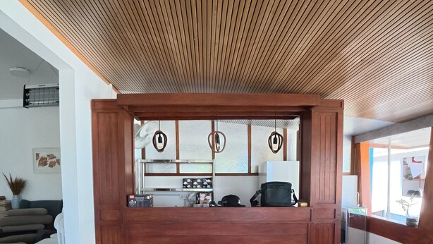 A reception area with a wooden ceiling, a reception desk, and a view of the outside. - VelaaOlhu - Turtle Hive Thulusdhoo (Thulusdhoo Island)
