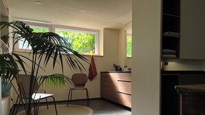 Eine moderne Küche mit Essbereich, einem Blumentopf und einem Fenster mit Blick auf Grünflächen.