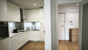 Een moderne keuken met witte kasten, een oven van roestvrij staal en een houten vloer.