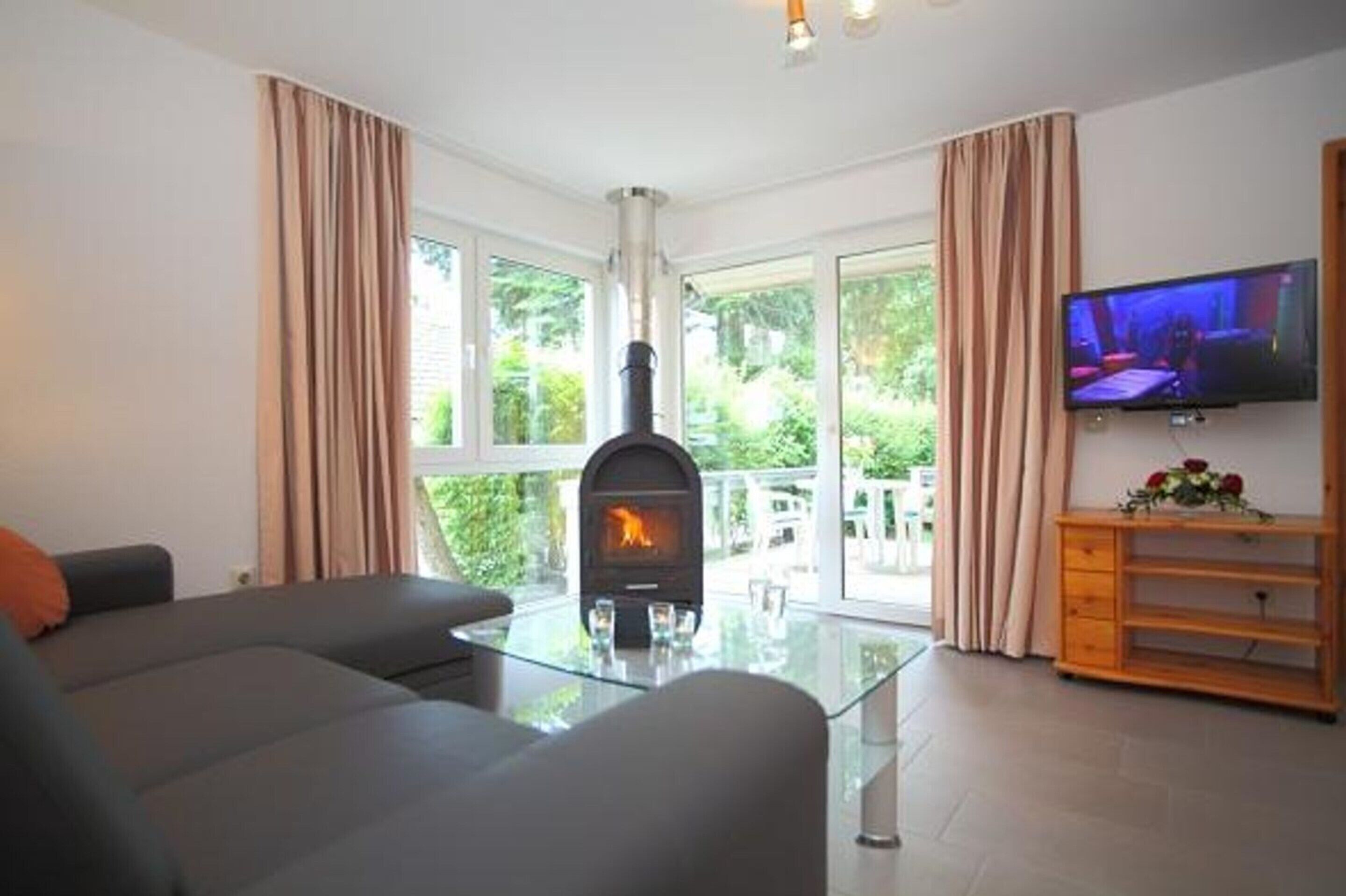 A living room with a fireplace, a sofa, a glass coffee table, and a television.