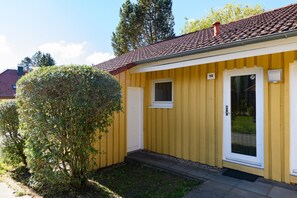 Ein gelbes Gebäude mit rotem Ziegeldach, einem kleinen Fenster und einer Tür.