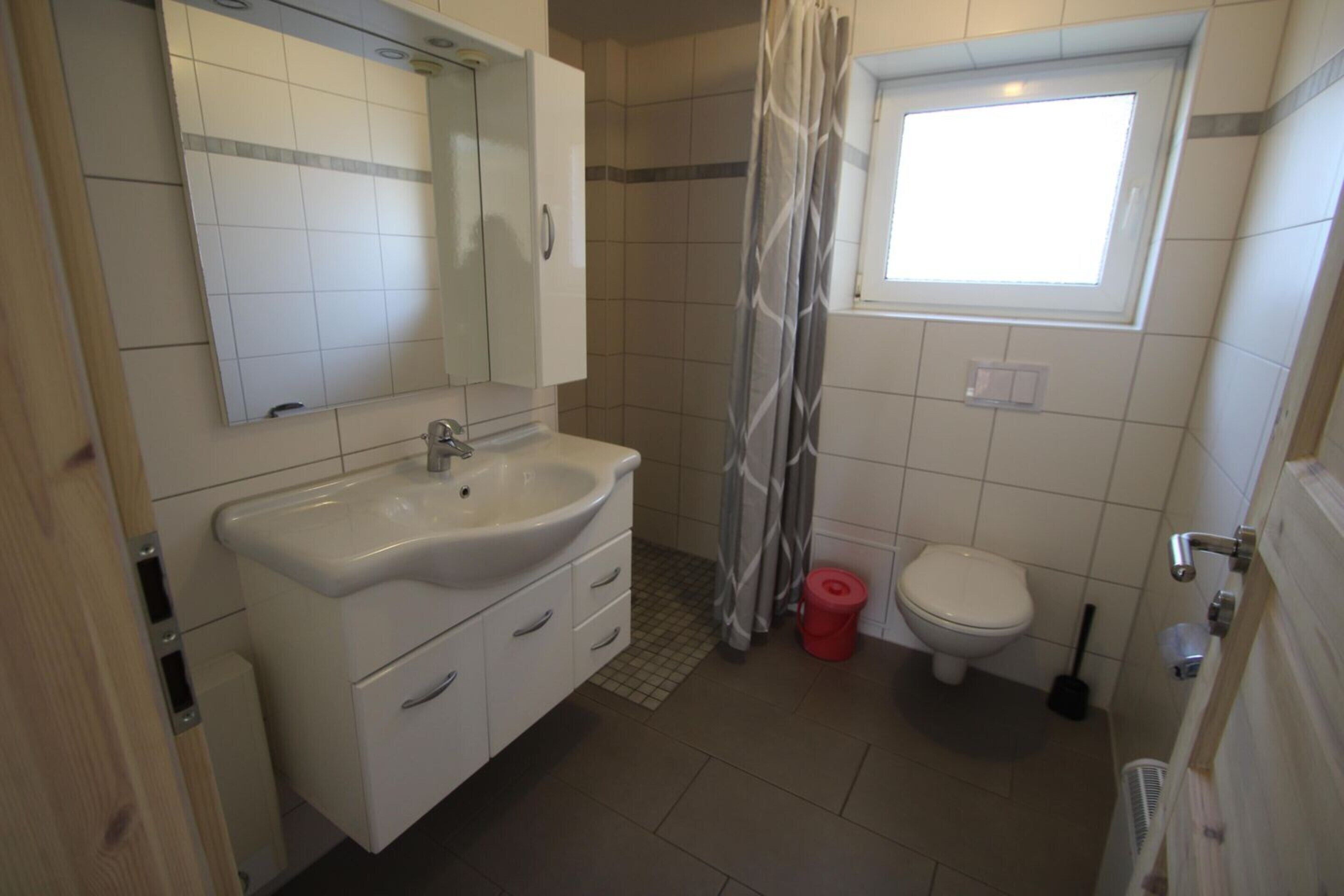 Un baño con lavamanos, espejo e inodoro blancos.