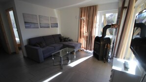 Uma sala de estar com sofá, mesa de centro de vidro, lareira e televisão.