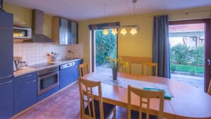 Cocina compacta con comedor, microondas, estufa y ventana con cortinas.