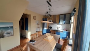 Un comedor con una mesa y sillas de madera, una cocina con armarios azules y un cuadro en la pared.