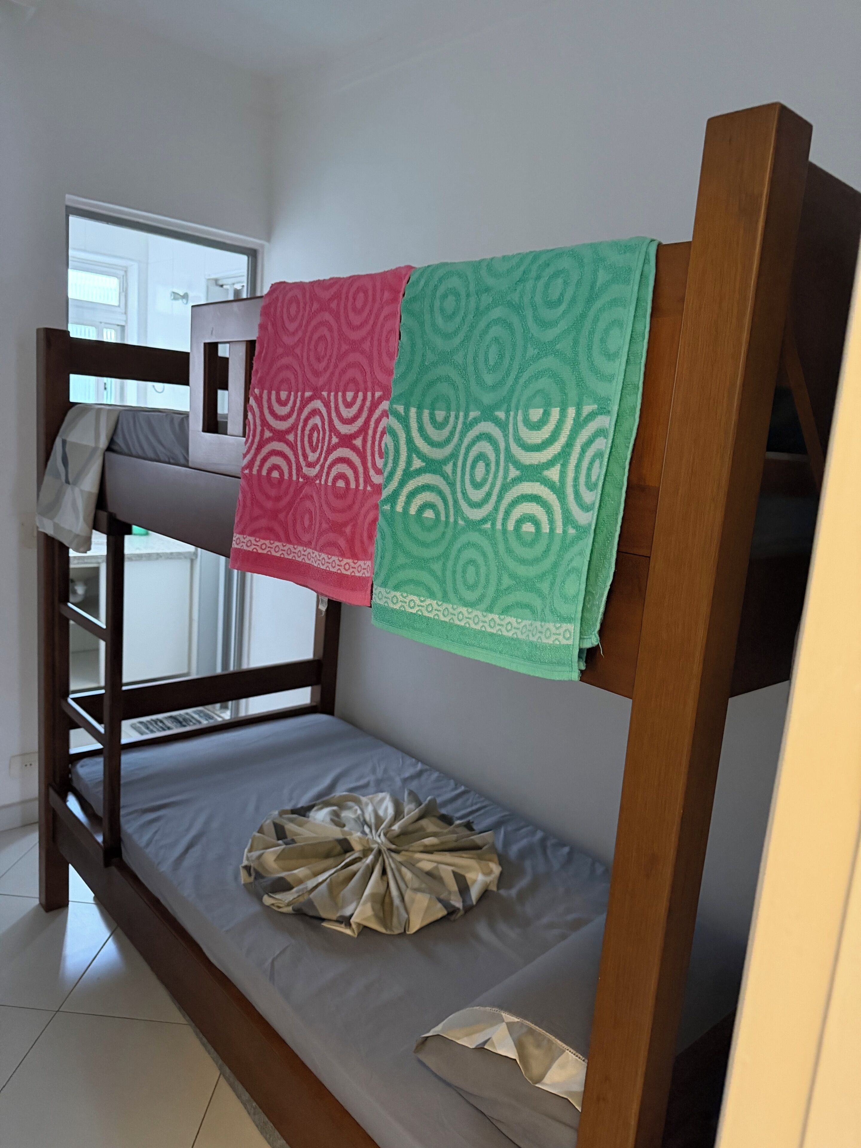 A bunk bed with a grey mattress and a patterned blanket.