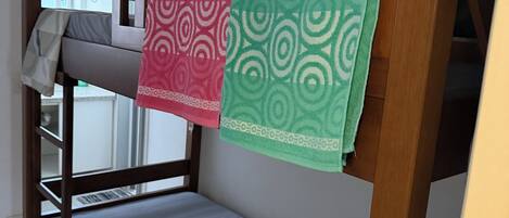 A bunk bed with a grey mattress and a patterned blanket.