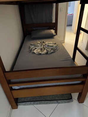 A single bed with a grey mattress and a blanket arranged in a circular pattern. - Cozy apartment in Guarujá, Enseada beach. (Guarujá)