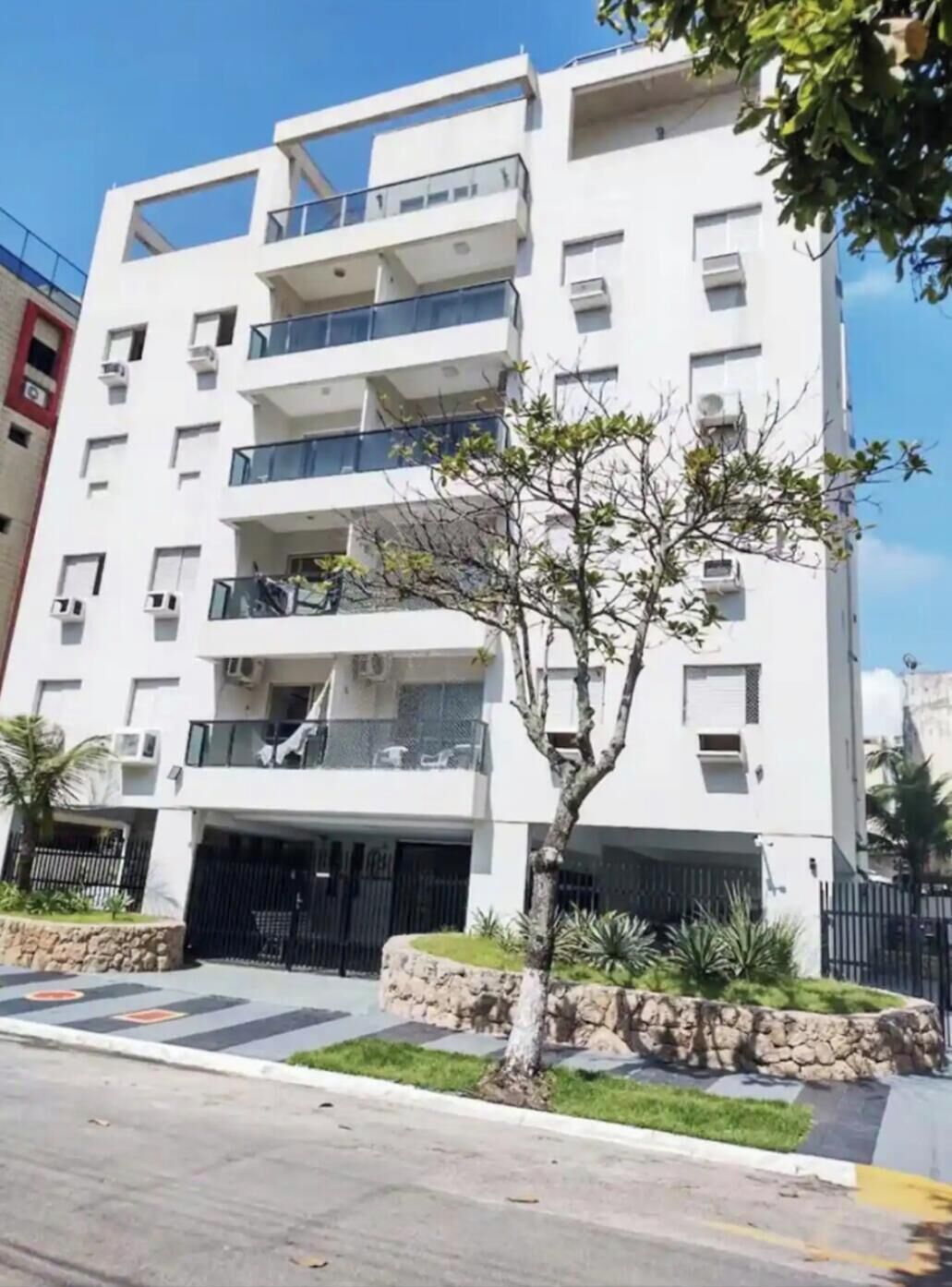 A multi-story residential building with balconies, air conditioning units, and a gated entrance.