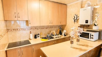 A kitchen with wooden cabinets, a built-in microwave, and a stone countertop.