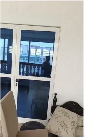A room with a sliding glass door leading to an outdoor balcony, a sofa with patterned cushions, and a chair. - Your cozy home, just a 5-minute walk from the beach (Cotonou)