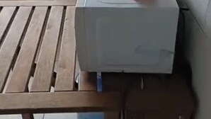 Una kitchenette pequeña con un microondas, un electrodoméstico rojo y un dispensador de agua.