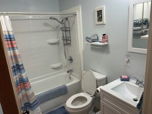 A bathroom with a shower, toilet, sink, and a towel rack. - Cozy 2-bedroom house in tranquil Put-in-Bay with AC (Put-in-Bay)