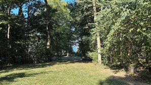 A grassy area with trees and a paved path. - Cozy 2-bedroom house in tranquil Put-in-Bay with AC (Put-in-Bay)