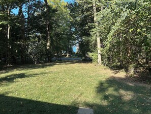 A grassy area with trees and a paved path. - Cozy 2-bedroom house in tranquil Put-in-Bay with AC (Put-in-Bay)