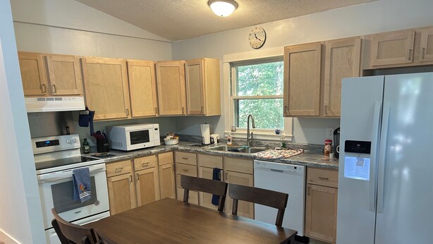 A kitchen with wooden cabinets, a microwave, a dishwasher, and a refrigerator. - Cozy 2-bedroom house in tranquil Put-in-Bay with AC (Put-in-Bay)