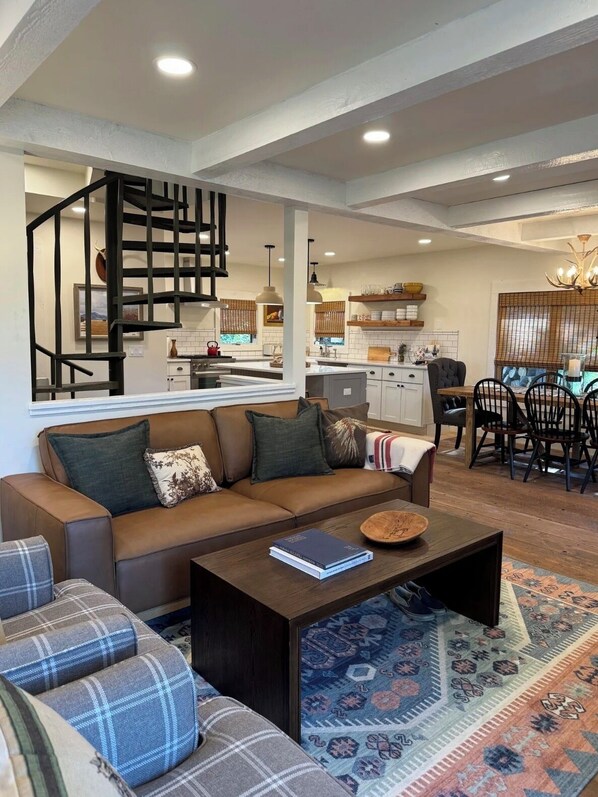 A modern living room with a sofa, a coffee table, and a dining area with chairs and a table.