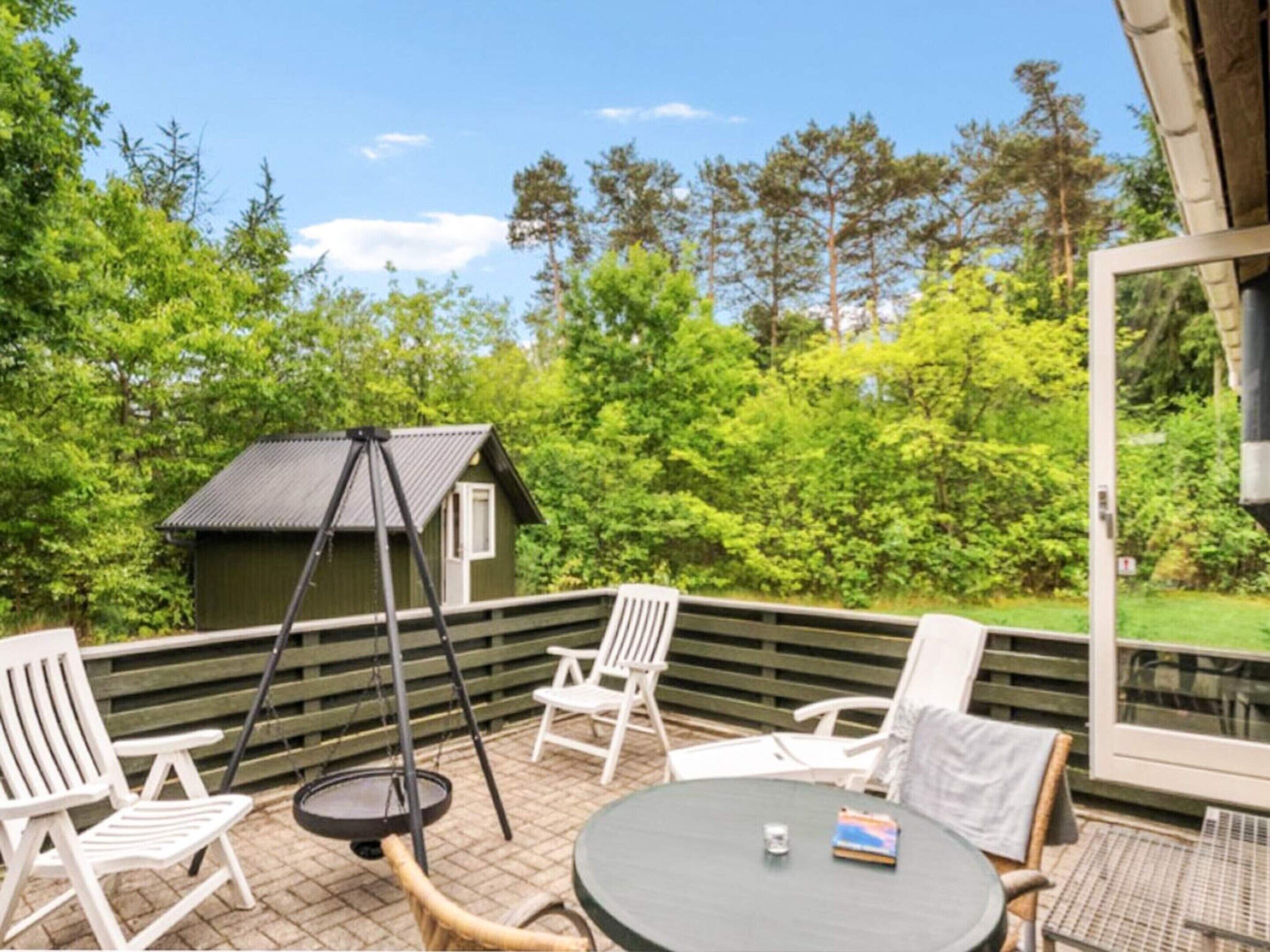 A patio with outdoor furniture, a swing, and a small shed.